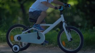 Aktif çocuk parkta bisiklet sürmeyi öğreniyor.