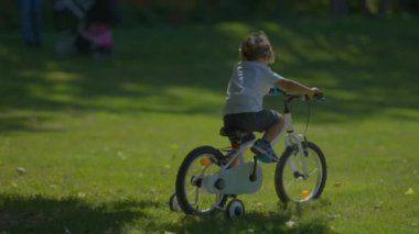 Aktif çocuk parkta bisiklet sürmeyi öğreniyor.