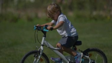 Parkın dışında bisiklete binen küçük çocuk aktif bisiklet sürüyor.