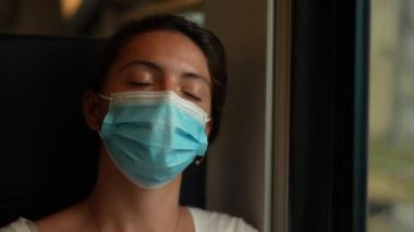 Trenle seyahat ederken yüzü morarmış bir maske takan kadın.