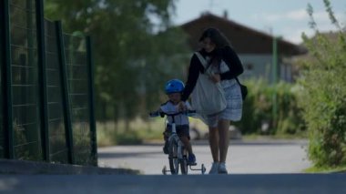 Bisiklete binen küçük çocuk dışarıda çocuk bisikleti sürüyor kaskla bisiklet sürüyor.