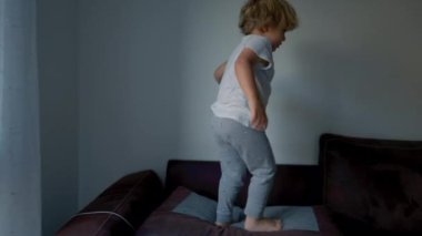 Aktif küçük çocuk evdeki kanepede zıplıyor.