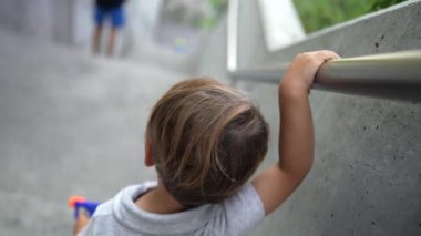 Bebek merdivenlerden inerken tırabzanlara tutunuyor. İstifa eden çocuk