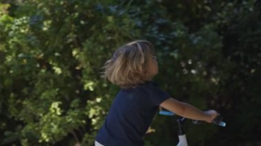 Dışarıda bisiklete binen çocuk zahmetli küçük çocuk bisiklet sürüyor.