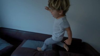 Çocuk kanepede zıplayıp duruyor.