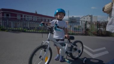 Şehir sokağında bisiklet taşıyan küçük çocuk.