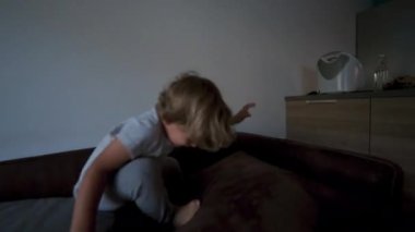 Evdeki kanepenin üstünde koşan aktif küçük çocuk.