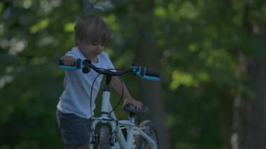 Küçük çocuk bisiklete biniyor ve tepeden aşağı iniyor.