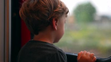 Yürüyen çocuk, tren penceresinin yanında durup hayal kuruyor.