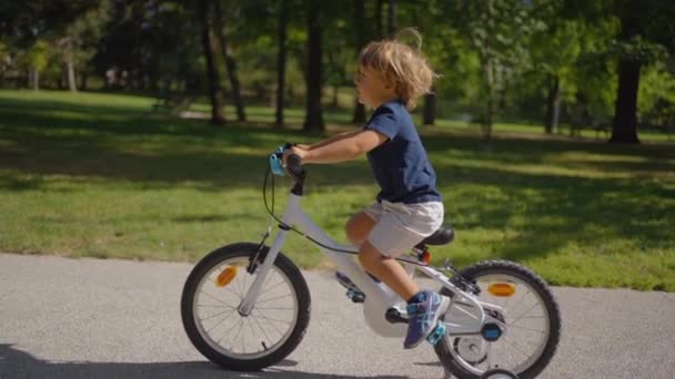 孩子们慢吞吞地骑自行车在公园外面 — 图库视频影像