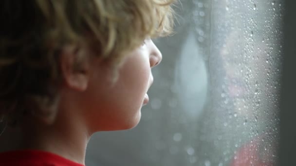 Ung Pojke Står Vid Fönstret Kall Regnig Dag Vill — Stockvideo