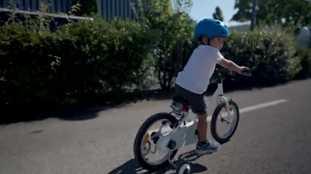 活泼的小男孩骑着自行车在外面绿路上戴着安全帽 — 图库视频影像