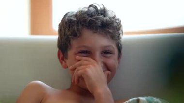 Kanepede oturmuş film izlerken gülümseyen samimi, küçük çocuk yüzü.