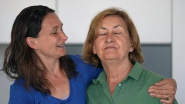 Yetişkin kız, farklı kuşaklardan, sevgi ve şefkat dolu bir anneyi yanaktan öpüyor.