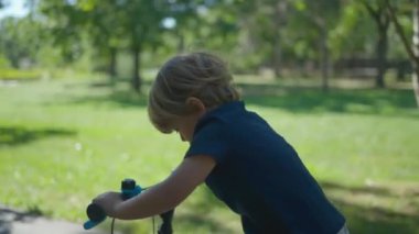 Aktif bir çocuk parkta bisiklet sürüyor.