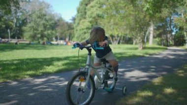 Aktif bir çocuk parkta bisiklet sürüyor.