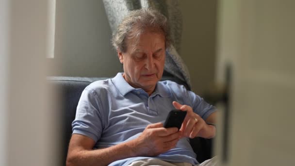 Ärlig Gammal Man Med Telefon Senior Person Sitter Soffan Tittar — Stockvideo
