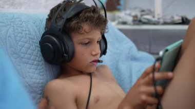 Çocuk, mikrofona bağlı online oyun ile video oyunu kulaklığı takıyor