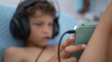 Çocuk, mikrofona bağlı online oyun ile video oyunu kulaklığı takıyor