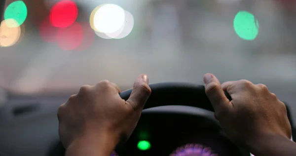 Driver POV hands holding steering wheel waiting. Person hand close-up point of view in red light