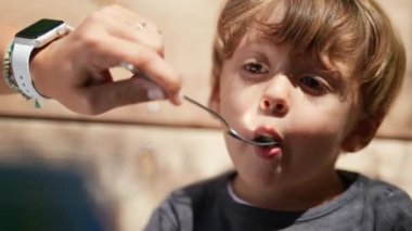 Feeding little boy food outside during lunch