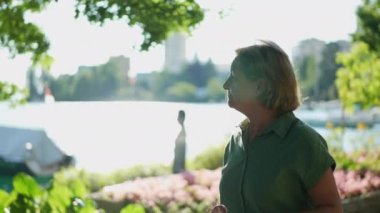 Yeşil şehir şehrinde dışarıda yürüyen yaşlı bir kadın, kıdemli kişi dışarıda yürüyor.