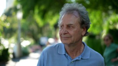 Mutlu bir yaşlı adam güneşli bir günde dışarıda yürüyor, düşünceli yaşlı bir adam.