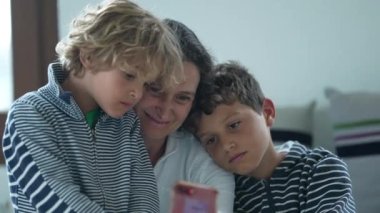 Anne ve çocuklar birlikte telefon ekranı izliyorlar. Ebeveynler ve çocuklar cep telefonuna bakıyor.