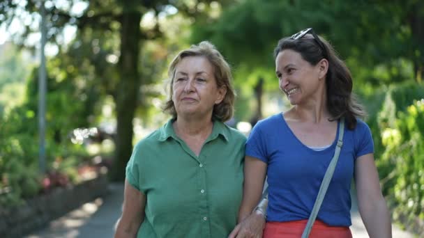 幸せな母親と大人の娘が緑の街を歩いて笑って笑顔 — ストック動画