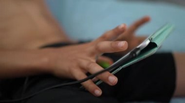 Küçük çocuk mikrofonlu kulaklık takarak tablet üzerinde video oyunu oynuyor.
