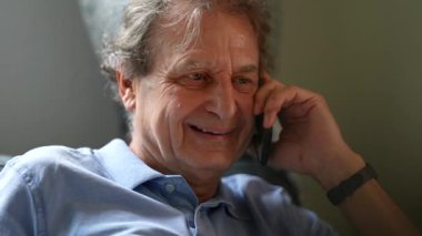 Yaşlı adam cep telefonundan gülümsüyor. Akıllı telefonda mutlu son sınıf konuşmaları.