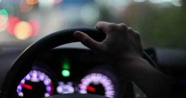 Female driver holding car steering wheel driving at night in city