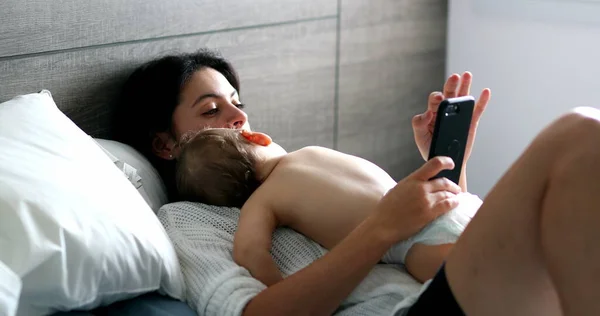 Повсякденна Мати Дивиться Мобільний Телефон Дитиною Занурюється Спальню Немовля Спить — стокове фото