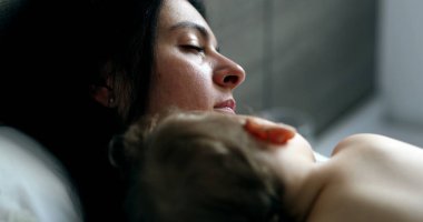 Baby and mother napping lying in bed