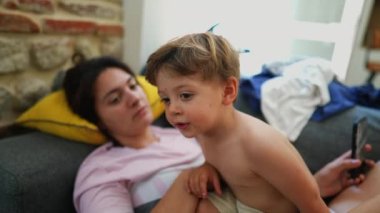 Çocuk ve anne evdeki kanepede birlikte rahat ve otantik.