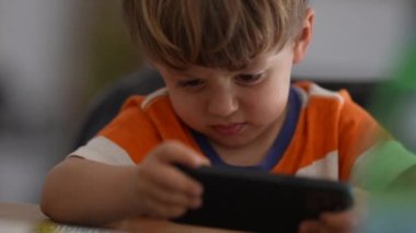 Annoyed little boy using phone upset child holding cellphone