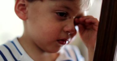 Elle gözlerini ovuşturan yorgun bir çocuk.