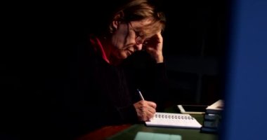 Geceleyin karanlıkta kağıda yazdığın düşünceli yaşlı kadın.