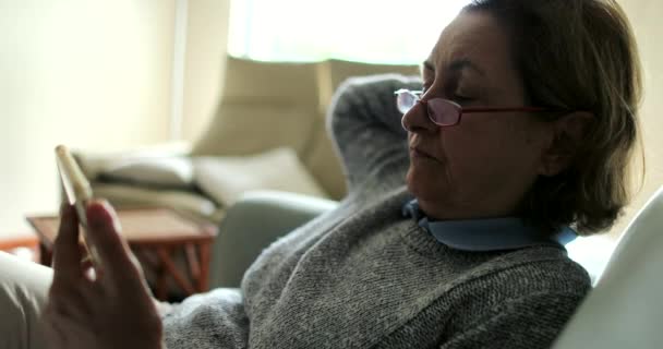 Kanepede Oturmuş Akıllı Telefon Ekranına Bakan Yaşlı Bir Kadın Internetten — Stok video
