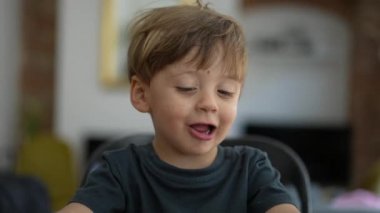 Mutlu çocuk ellerle masaya vurup meyve yiyor.