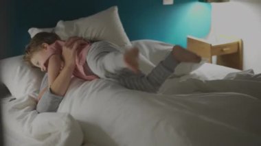 Çocuk yatakta annesine atlıyor.