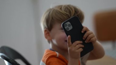 Çocuk elinde akıllı telefon tutan çocukla fotoğraf çekiyor.