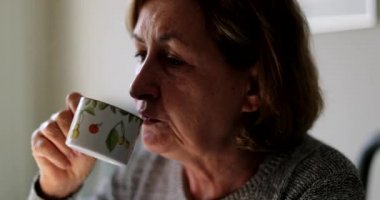 Yaşlı kadın kahve ya da çay içiyor.