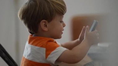 Samimi çocuk elinde akıllı telefon tutarak teknolojiyi kullanıyor.