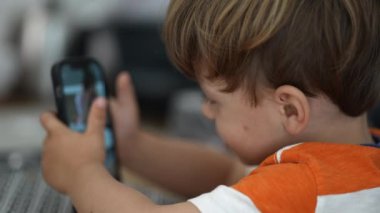 Telefonu kullanan çocuk akıllı telefonuyla fotoğraf çekmeye çalışıyor.