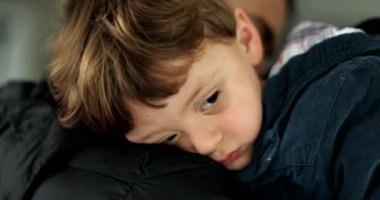 Uykulu çocuk annesinin omzunda, yorgun çocuk uykuya dalıyor.