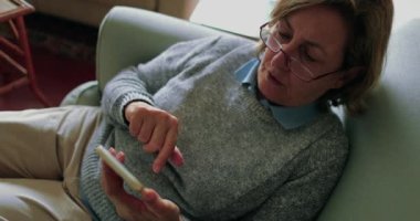 60 'lı yaşlarda teknolojiyi kullanan yaşlı bir kadın akıllı telefondan mesaj atıyor.