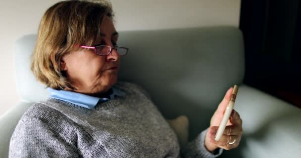 Donna Anziana Che Guarda Contenuti Sul Dispositivo Smartphone Seduto Sul — Video Stock