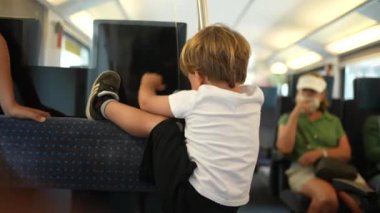 Küçük yaramaz çocuk, tren koltuğuna tırmanıyor.