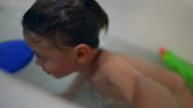 Küvetin içindeki küçük çocuk banyo yapıyor.